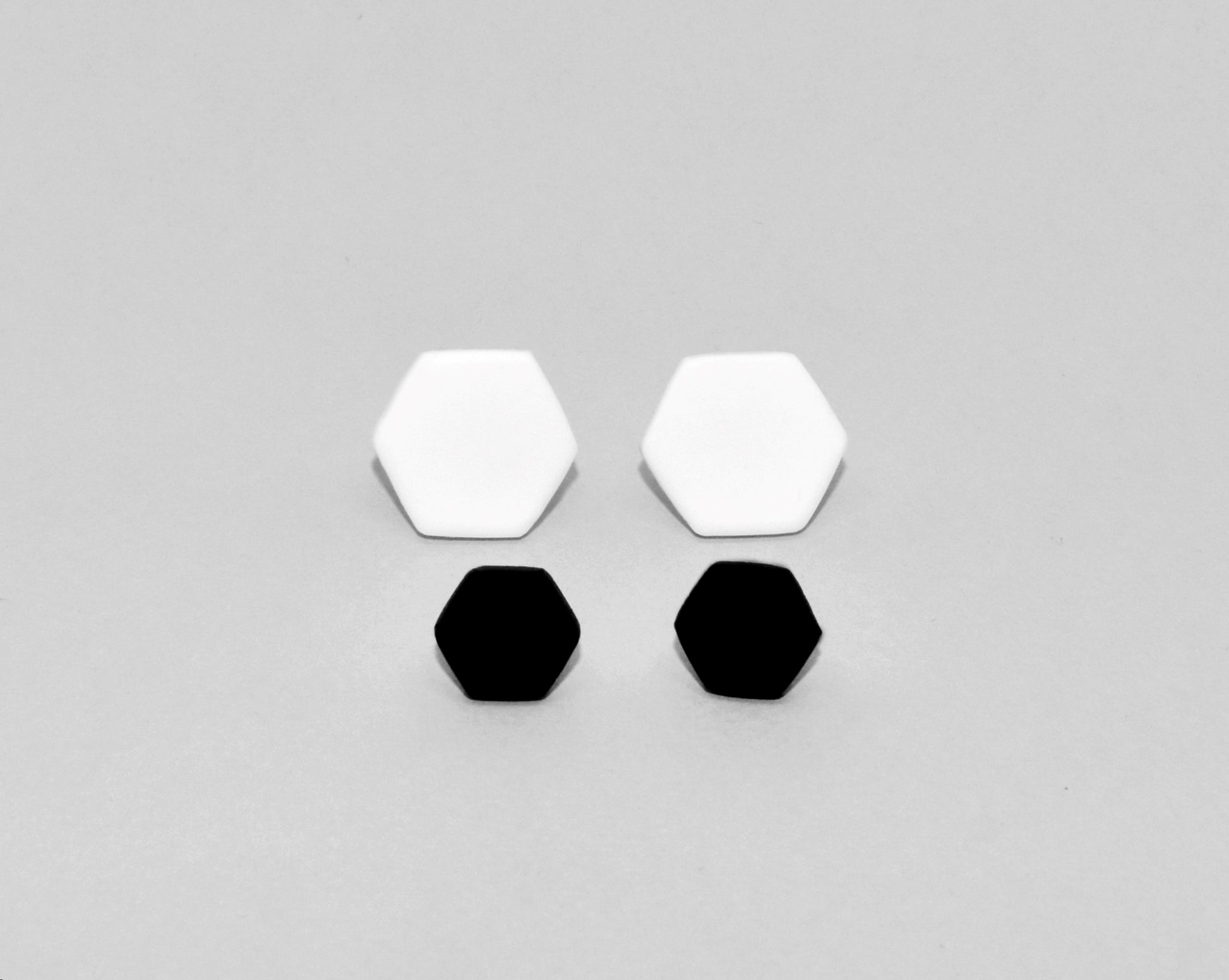 Display of 2 different sizes of Matte black hexagon stud earrings handmade from polymer clay by Vertseas.