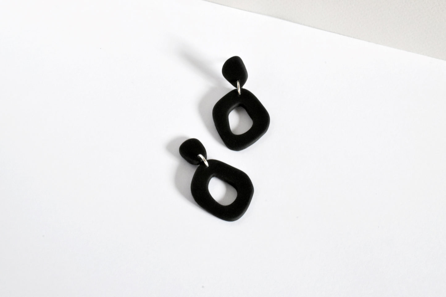 Matte black organic shape hoop earrings handmade from polymer clay.