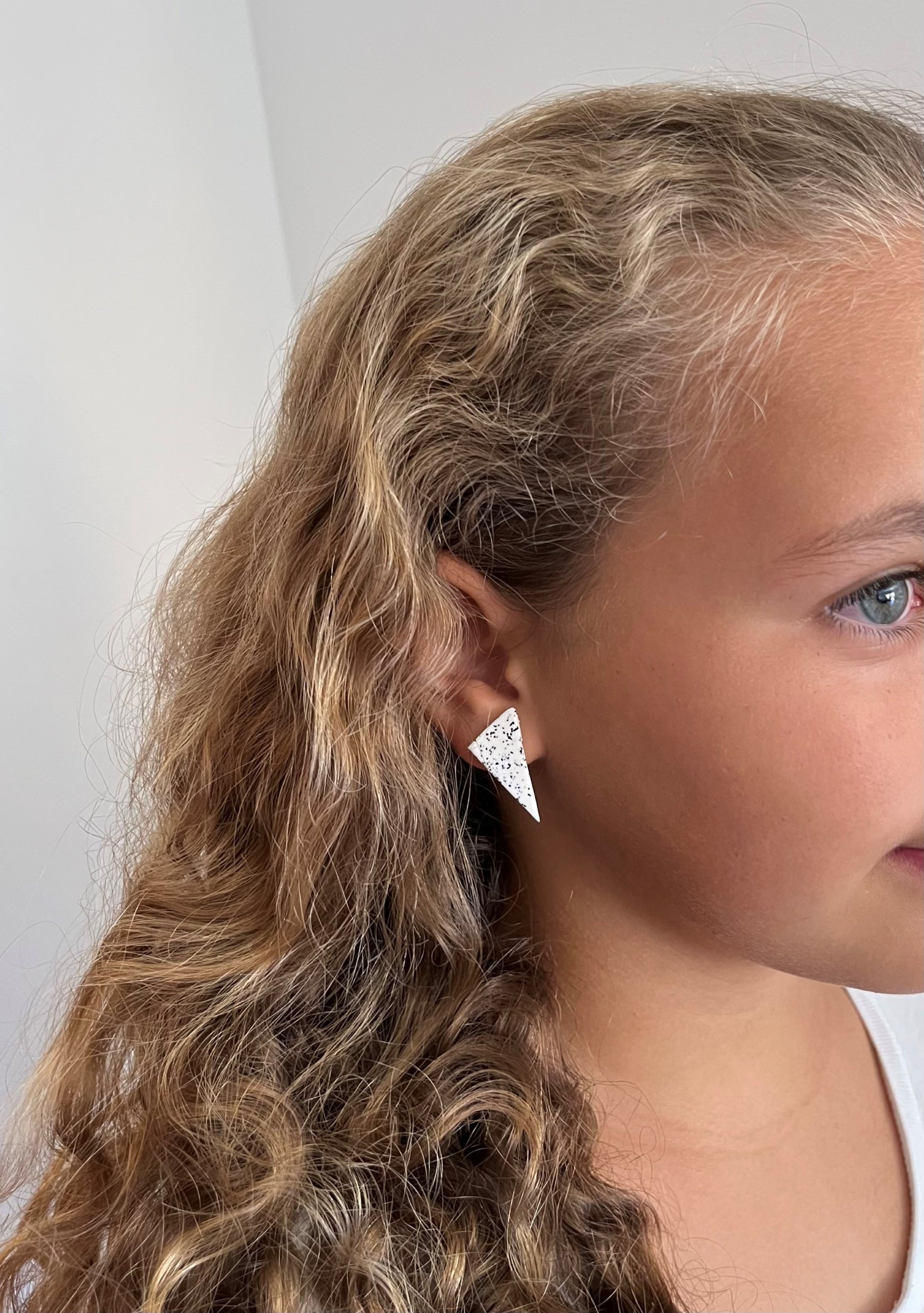 Model wearing triangle stud earrings handmade from polymer clay by Vertseas.
