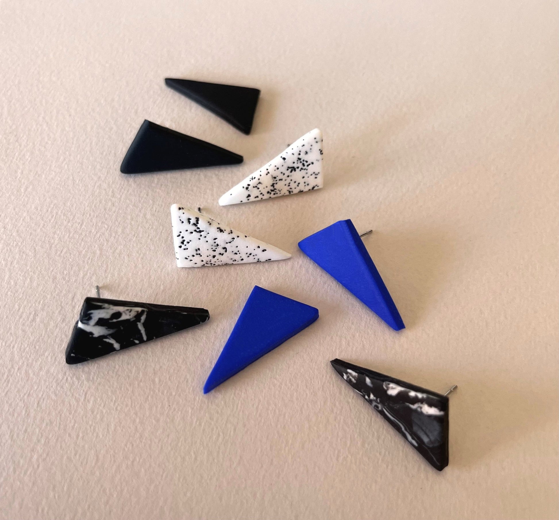 Display of triangle stud earrings in different colours handmade from polymer clay by Vertseas.